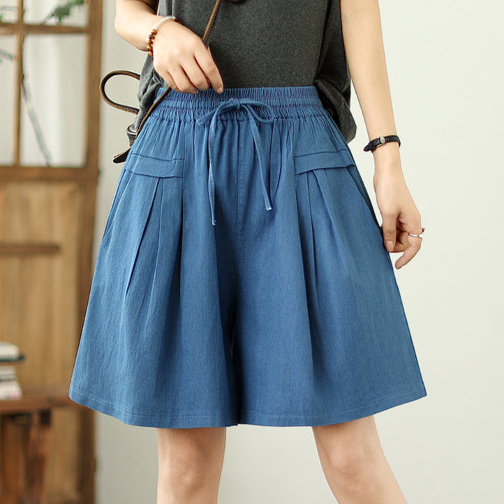 Person wearing a blue denim skirt with a neutral background