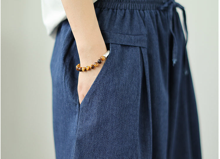 Blue denim skirt with a hand in the pocket on a plain background