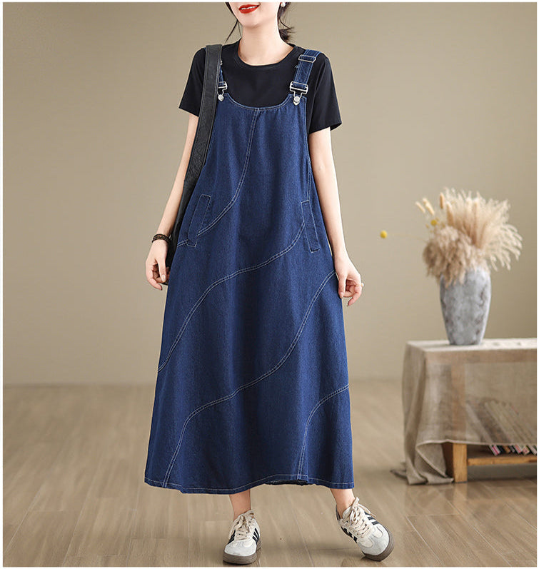 Person wearing a blue denim dress over a black t-shirt in a minimalistic setting.