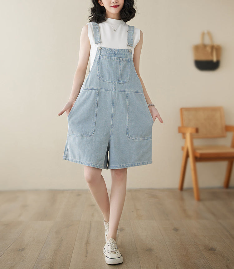 Woman wearing a light blue denim dress with a white top in a room with wooden floor and chair.