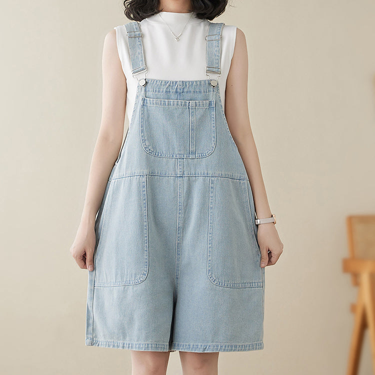 Woman wearing a light blue denim overall dress against a beige background