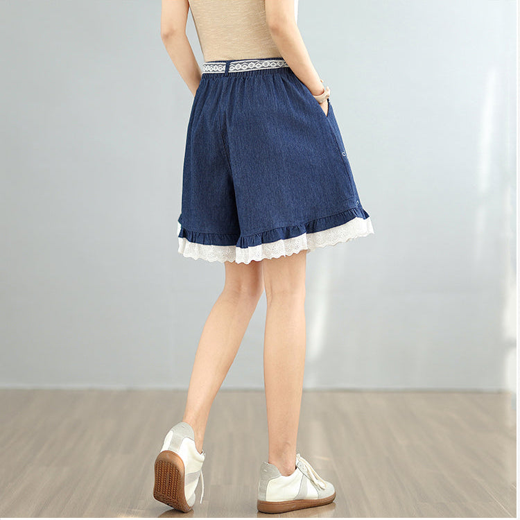 Person wearing a blue denim skirt with white lace trim on a plain background