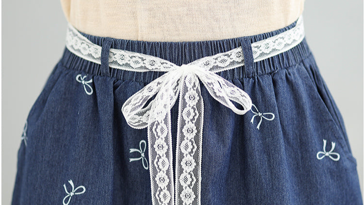 Blue denim apron with white lace trim and decorative bows on a gray background