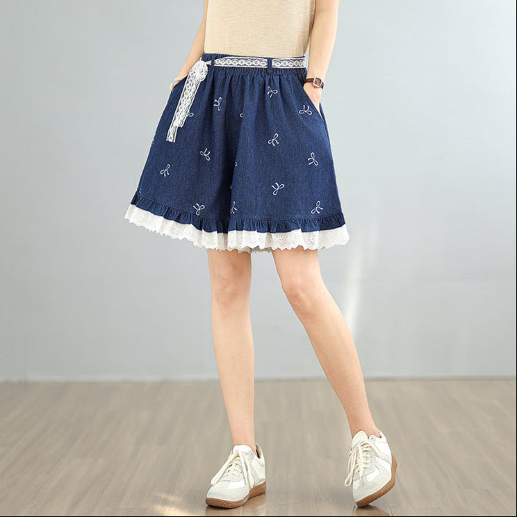 Person wearing a blue denim skirt with white lace trim on a plain background