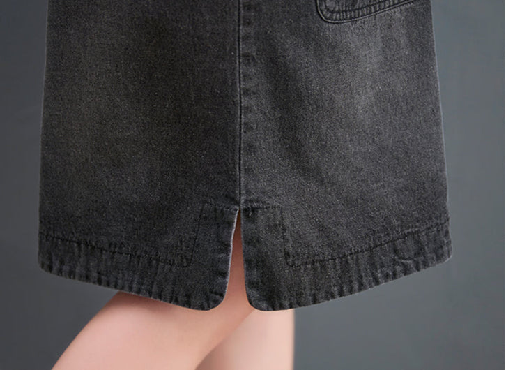 Close-up of a person wearing black denim shorts with a pocket detail on a gray background.