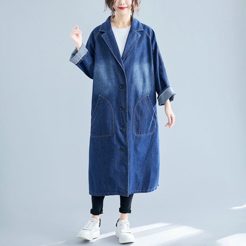 Person wearing a long blue denim coat on a light gray background
