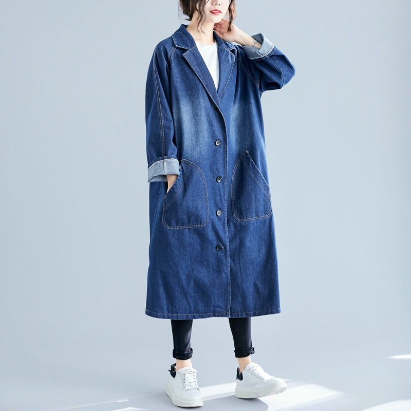 Person wearing a long denim coat on a light gray background