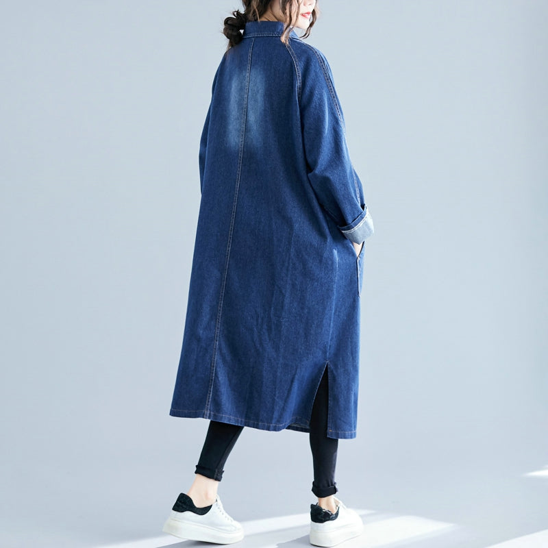 Person wearing a long blue denim coat on a light gray background