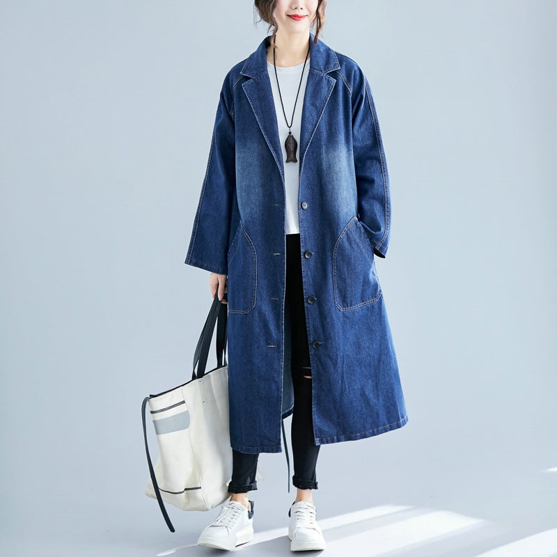 Person wearing a long blue denim coat holding a white tote bag on a light gray background
