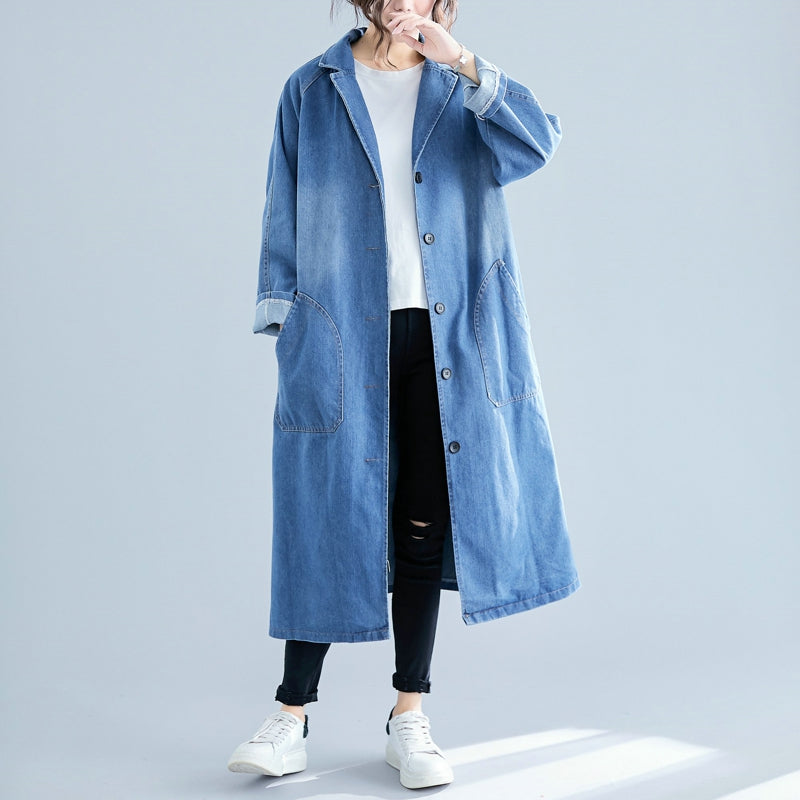 Person wearing a long denim coat on a light gray background