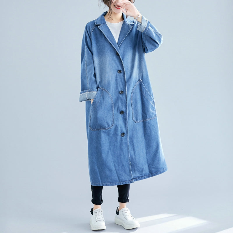 Person wearing a long denim coat on a light gray background