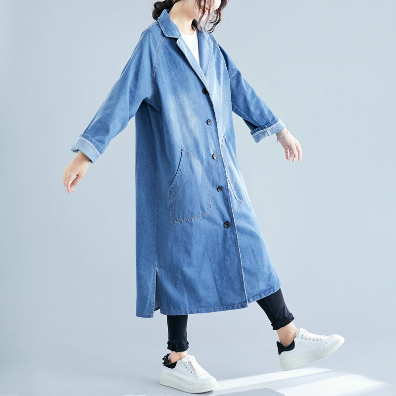Person wearing a long denim coat on a light gray background