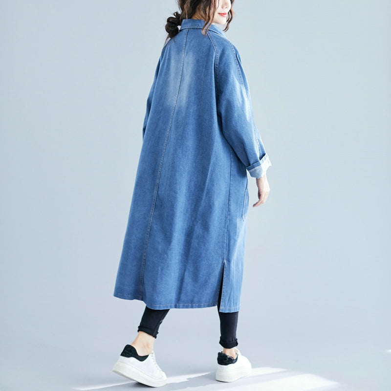 Person wearing a long blue denim coat on a light gray background