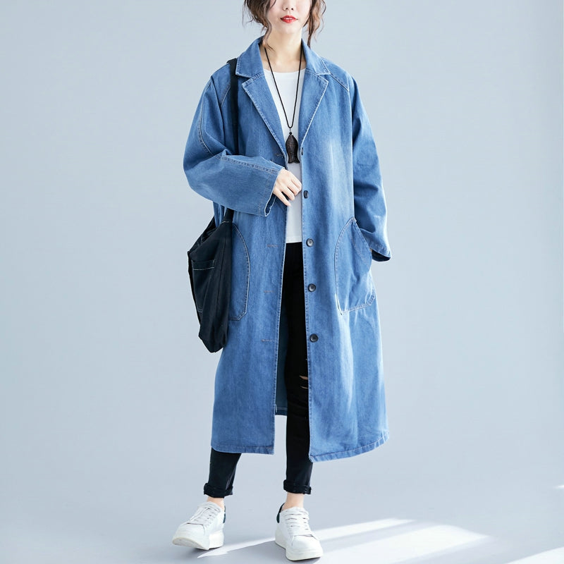 Person wearing a long denim coat on a light gray background