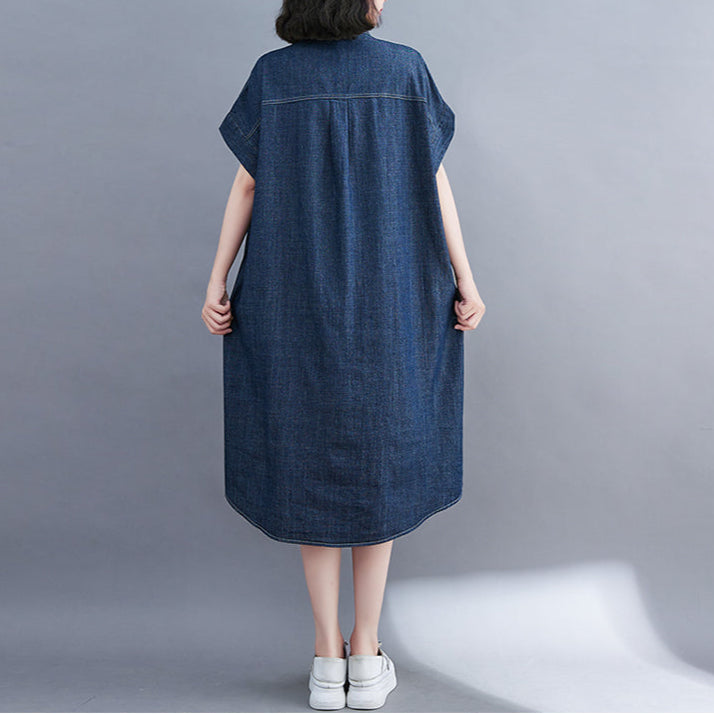 Person wearing a blue denim dress against a gray background