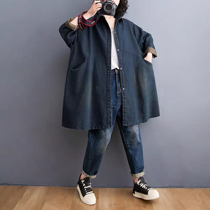 Person wearing a long denim shirt and jeans against a plain background