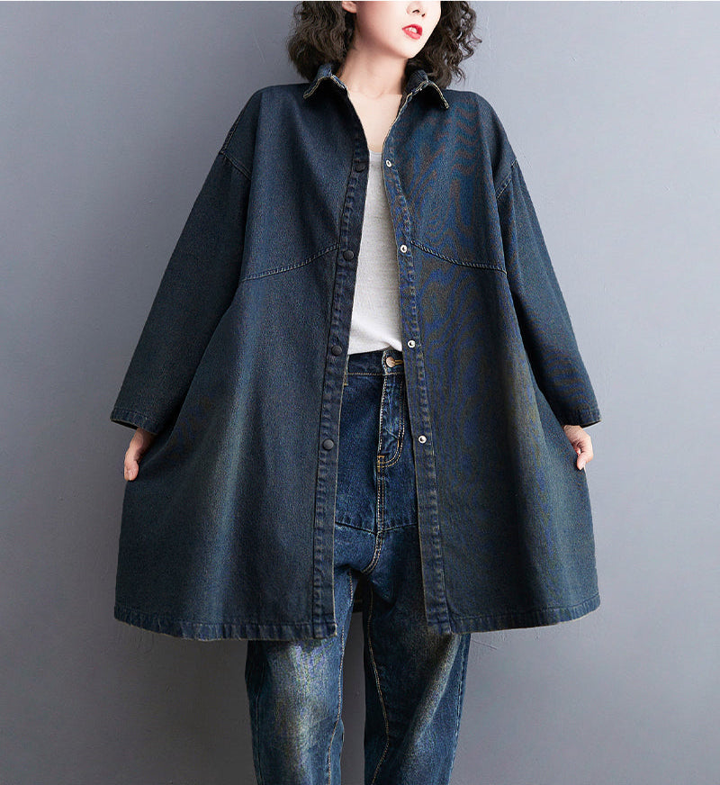 Person wearing a long denim coat on a gray background