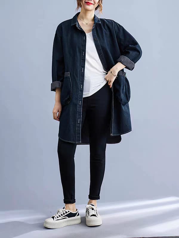Person wearing a dark denim shirt over a white top, black pants, and white sneakers on a gray background