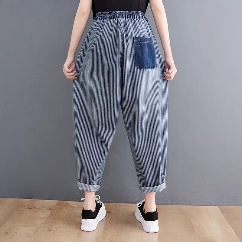 Person wearing blue striped pants with a pocket on a gray background