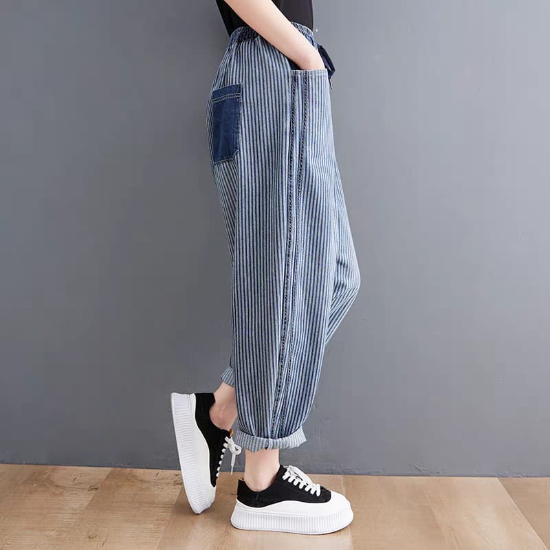 Person wearing blue striped pants and black sneakers against a gray background