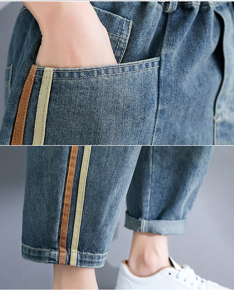 Close-up of blue jeans with colorful side stripes on a gray background