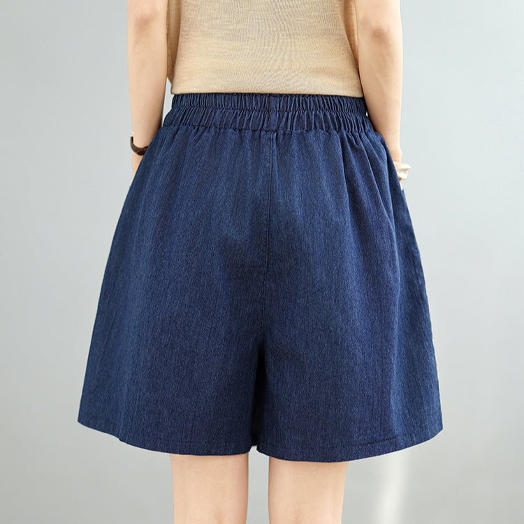 Blue denim shorts worn by a person on a gray background