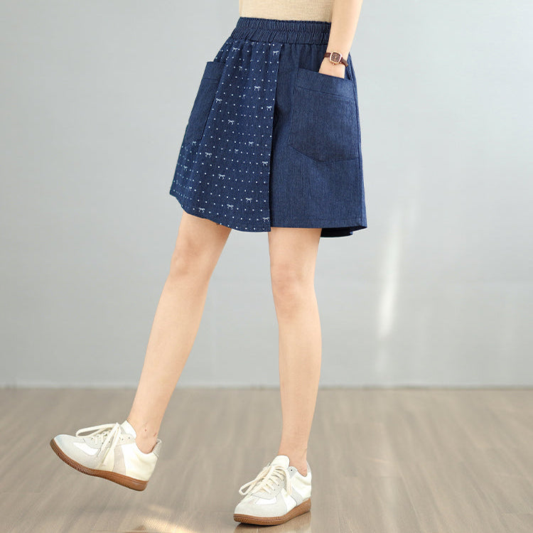 Person wearing a blue denim skirt with white polka dots on a plain background