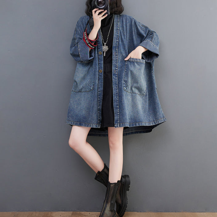 Person wearing a denim jacket over a black dress against a gray background