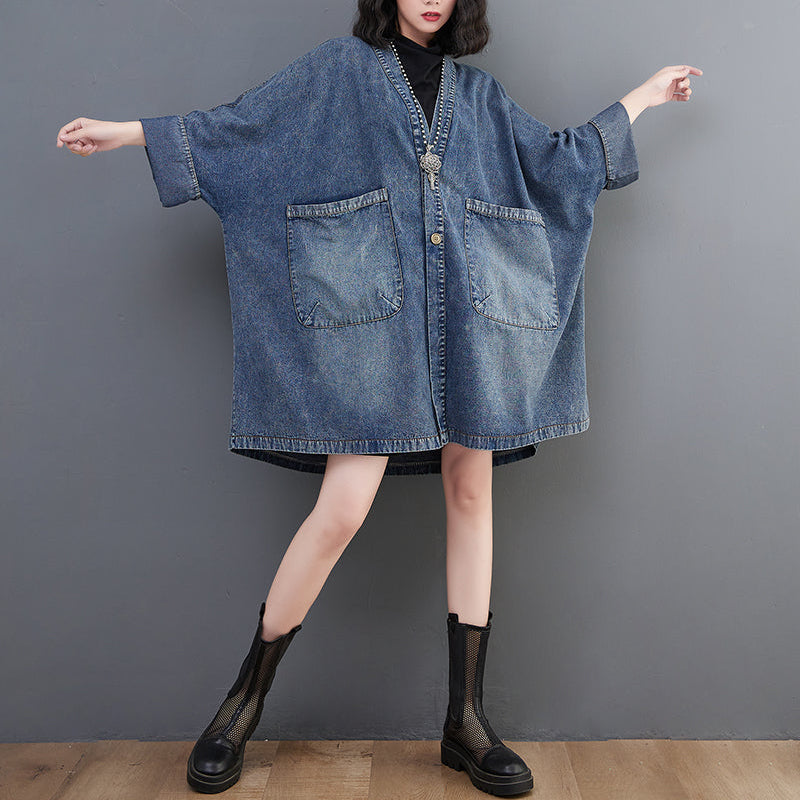 Person wearing a blue denim dress with a plain background