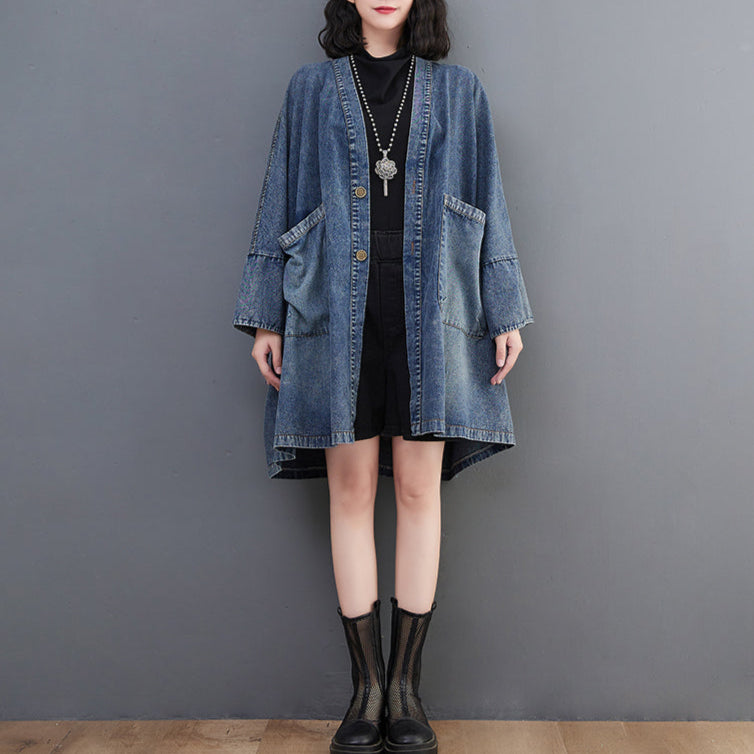 Person wearing a denim cardigan over a black outfit against a gray background