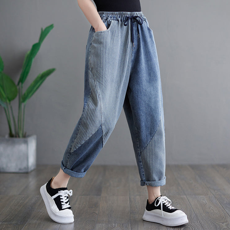 Person wearing blue striped jeans and black and white sneakers on a gray background