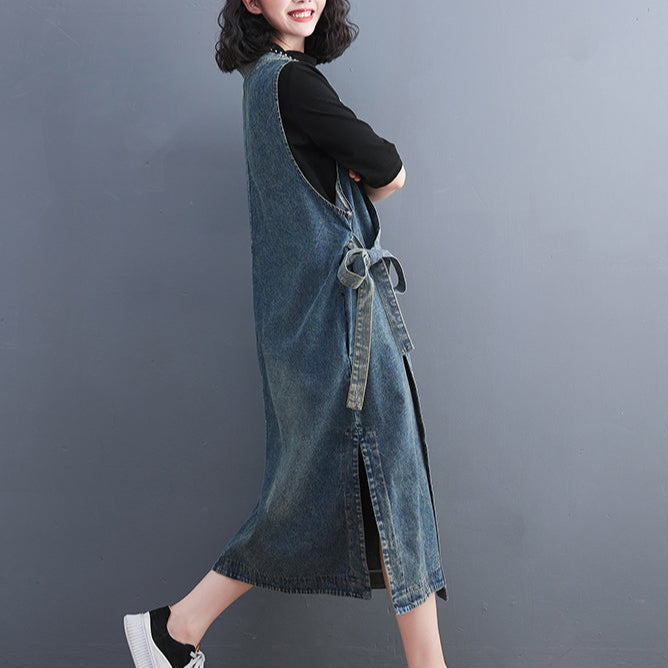 Person wearing a denim dress with a black top against a gray background