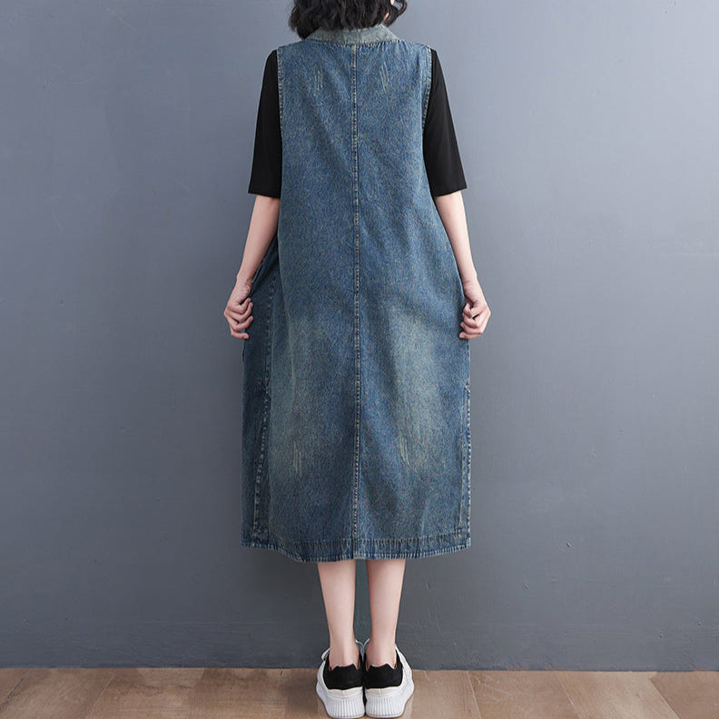 Person wearing a denim dress over a black top against a gray background