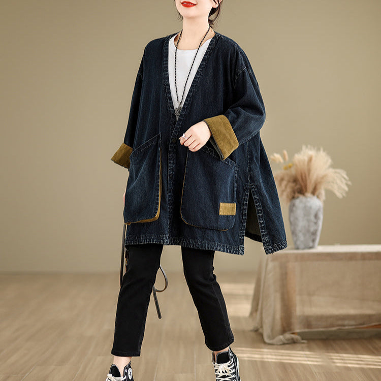 Person wearing a dark denim jacket with brown trim in a room with a wooden floor and beige walls.