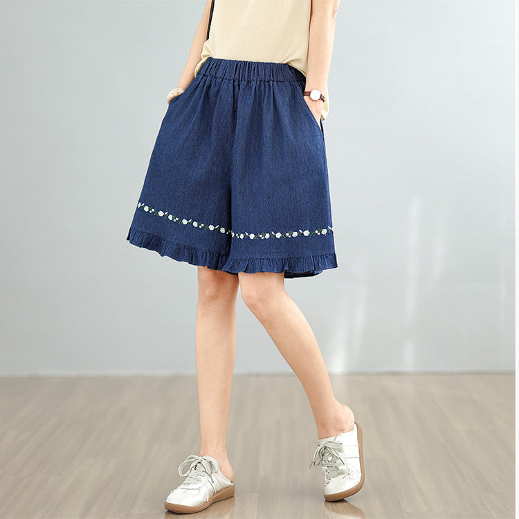 Person wearing blue denim shorts with white trim on a plain background