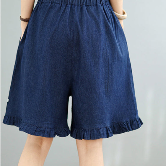 Person wearing blue denim shorts on a gray background