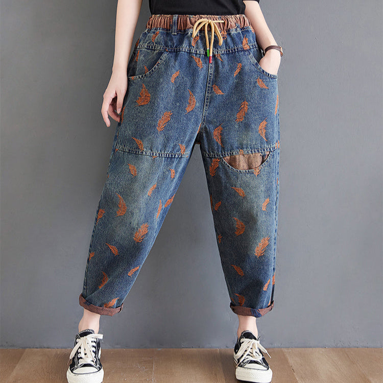 Person wearing blue jeans with brown patterns on a gray background
