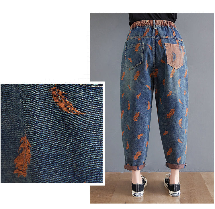 Blue denim jeans with orange feather patterns on a gray background