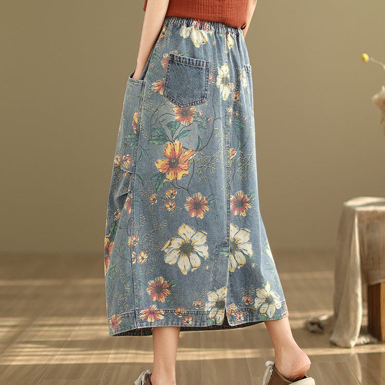 Person wearing a floral denim skirt in a room with wooden floor and beige wall.
