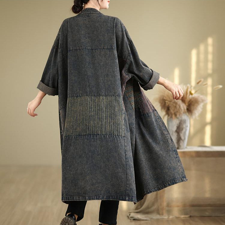 Person wearing a long denim dress in a room with wooden floor and beige wall.