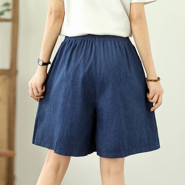 Person wearing a blue denim skirt on a plain background