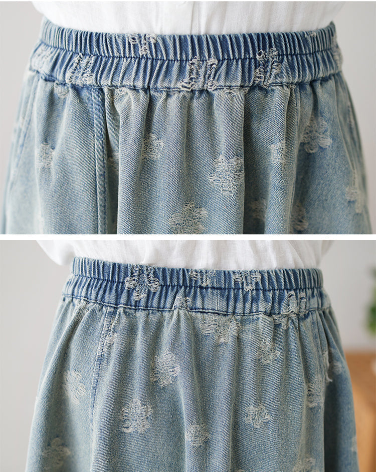 Light blue denim skirt with floral embroidery on a white background