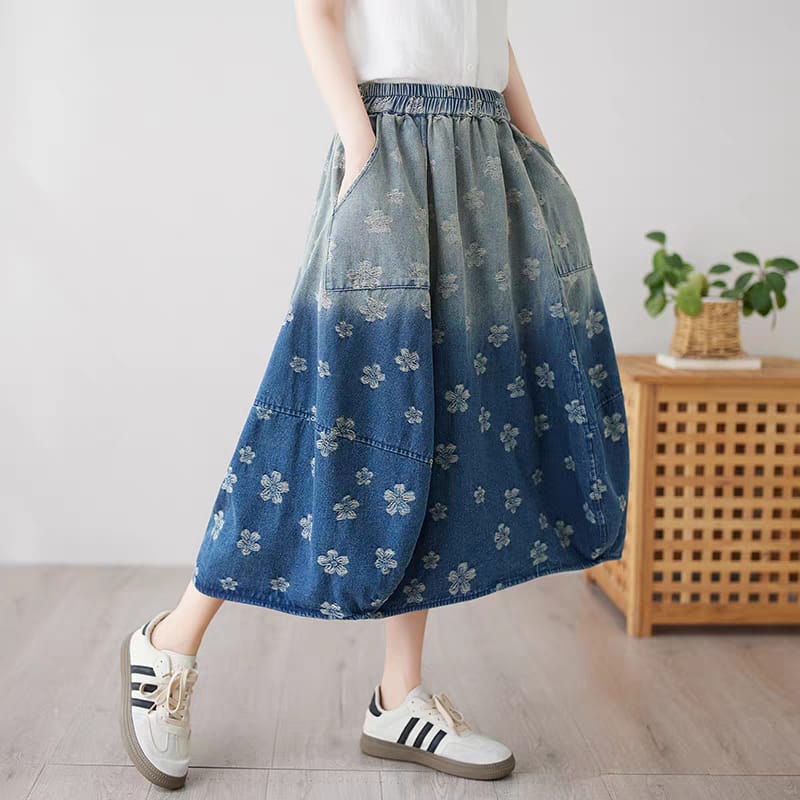 Person wearing a blue floral denim skirt with white sneakers in a room setting.