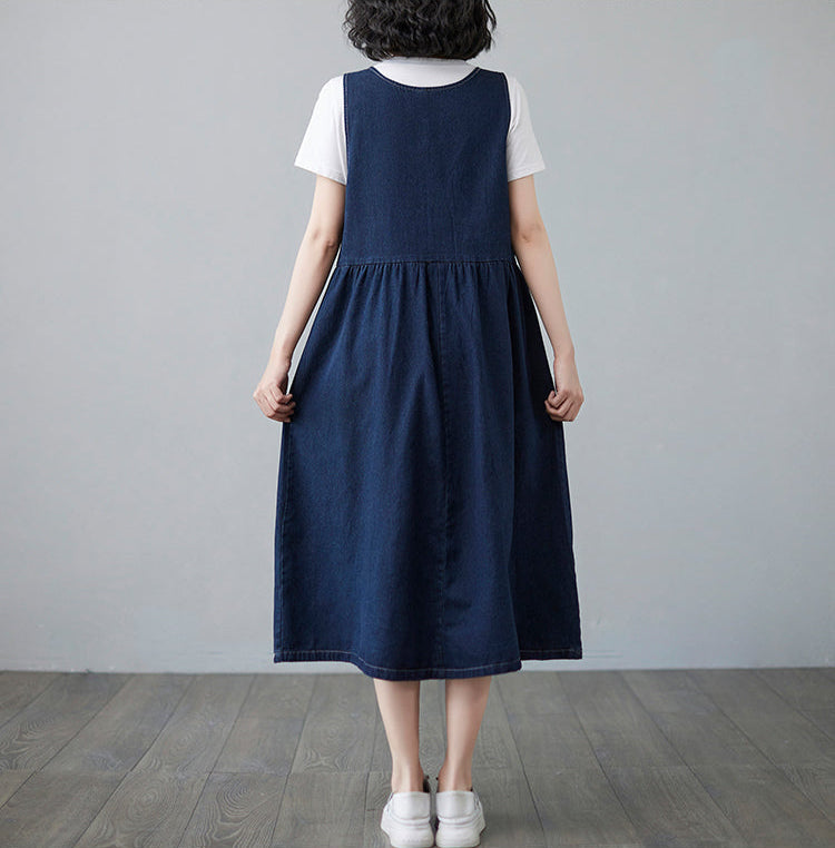 Person wearing a navy blue dress over a white shirt against a gray background