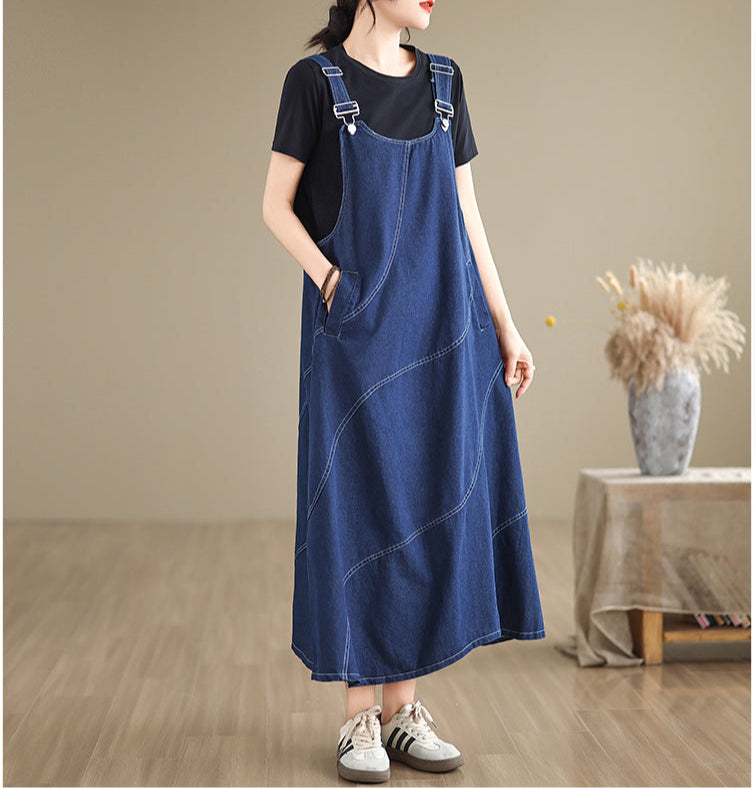 Woman wearing a blue denim dress over a black shirt in a minimalistic room.