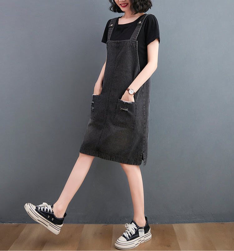 Person wearing a black denim dress with a plain background
