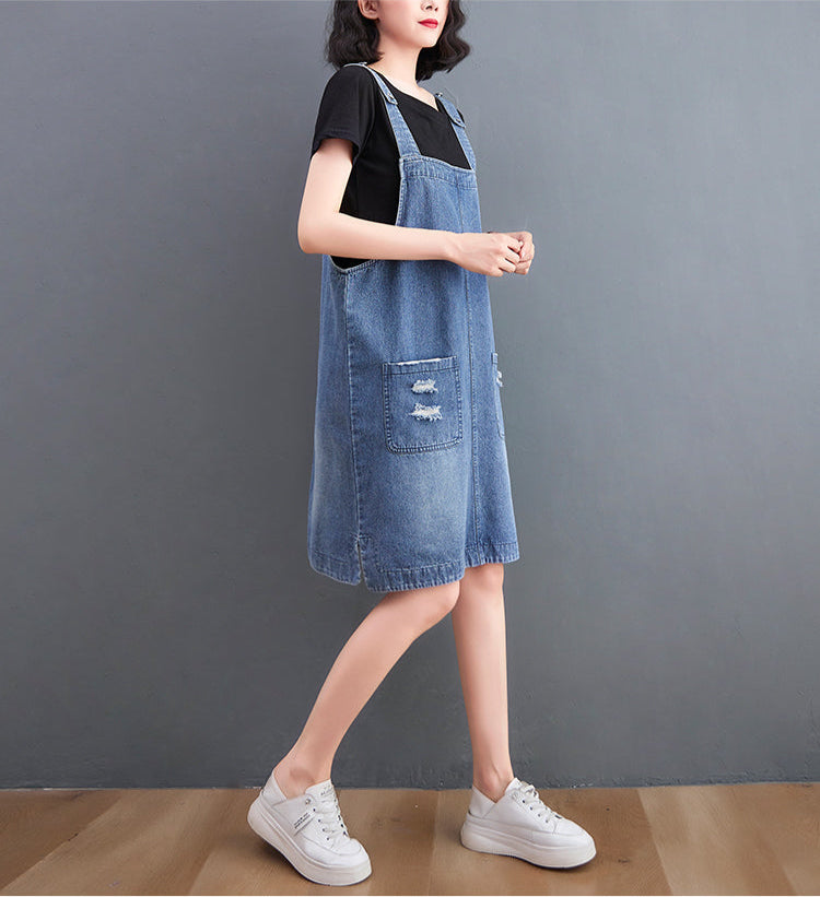 Person wearing a denim dress and white sneakers on a plain background