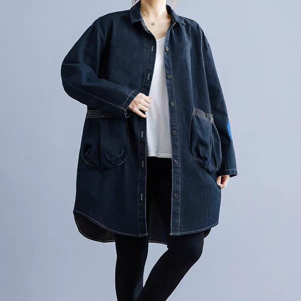 Person wearing a dark denim jacket over a white shirt and black pants on a gray background