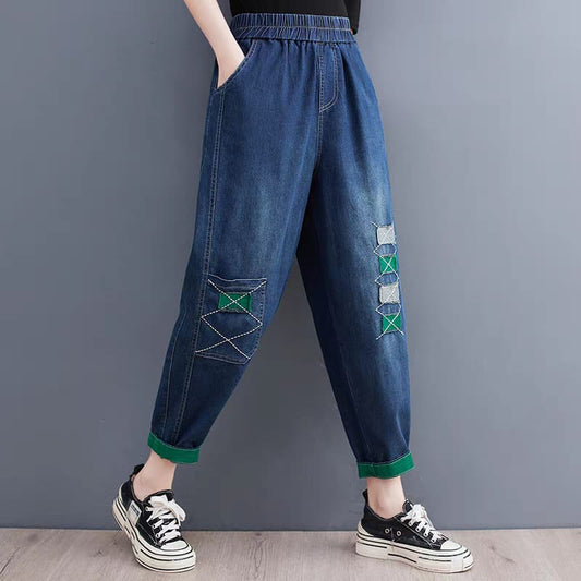 Blue denim pants with patches worn by a person against a gray background