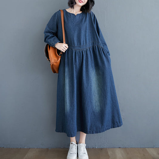 Person wearing a blue denim dress with a brown bag against a gray background